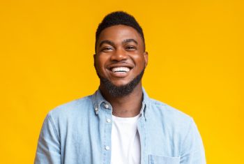 Portrait Of Young Laughing African American Guy Over Yellow Background